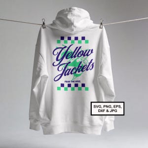 Pode incluir: Moletom branco com capuz pendurado em um varal. As costas apresentam as palavras "Yellow Jackets" em uma fonte estilizada, com um design verde e roxo. O texto "FEAR THE HIVE" está abaixo.