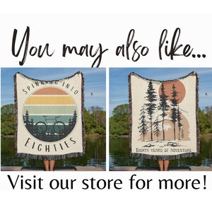 May include: Two woven throw blankets with nature-themed designs. One features a bicycle and the text "Spinning into Eighties" within a sunset circle. The other displays trees and a sun with the text "Eighty Years of Adventure".