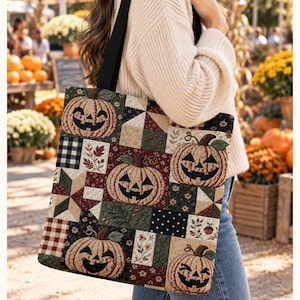 May include: A rectangular tote bag featuring a patchwork design with black fabric straps. The pattern consists of squares displaying jack-o'-lanterns, black and white buffalo check, floral motifs, and geometric shapes in shades of orange, green, and brown.