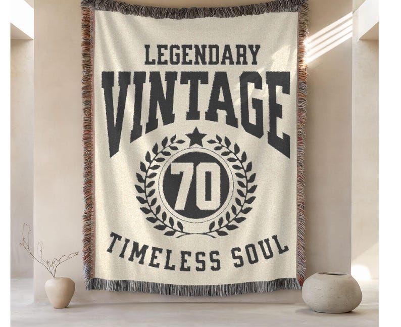 May include: Cream-colored woven throw blanket with black text that reads "LEGENDARY VINTAGE 70 TIMELESS SOUL." The blanket has a black and brown fringe.
