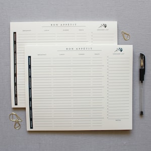 Puede incluir: Dos hojas blancas de planificador de comidas imprimibles con un borde azul y negro. La hoja superior tiene las palabras "Bon Appetit" y una sección de lista de la compra. La hoja inferior tiene los días de la semana enumerados en el lado izquierdo y columnas para el desayuno, el almuerzo, la cena y la merienda. La hoja inferior también tiene una sección de lista de la compra y una sección de notas.