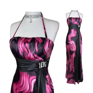 May include: A floor-length halter dress featuring a black and vibrant pink marbled pattern. The dress includes a solid black satin waistband adorned with a rectangular rhinestone brooch and a matching rhinestone choker necklace on the mannequin.