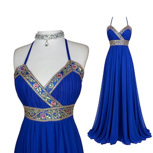 Könnte beinhalten: Ein bodenlanges, königsblaues Neckholder-Kleid mit V-Ausschnitt und einem breiten Taillenband, das mit bunten Pailletten und Perlen verziert ist. Das Oberteil ist gerafft und der Rock fällt bis zum Boden. Ein silberfarbenes Kristall-Halsband liegt bei.