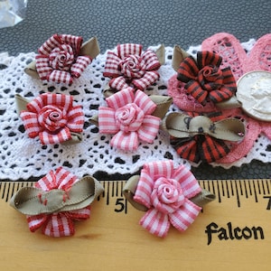 May include: Assortment of 10 handmade fabric flowers in red, pink, and white gingham patterns with green leaves. The flowers are approximately 1 inch in diameter and are perfect for adding a touch of whimsy to crafts, cards, and other projects.