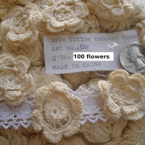 May include: A collection of cream-colored, crocheted flower appliques. The image includes a tag that reads "100% Cotton Crochet Flower" and "100 flowers". A white lace trim is also visible.