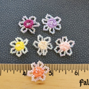May include: Five small beaded flower embellishments in various colors, including pink, purple, yellow, and orange. The flowers are approximately 1 inch in diameter and are shown next to a ruler.