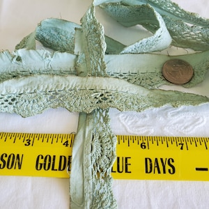 May include: Pale green vintage lace trim with a scalloped edge and a crocheted design. A yellow ruler with the text "SON GOLDEN BLUE DAYS" is in the foreground. A quarter coin is also visible.