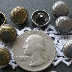 May include: Assortment of 10 metal buttons with a raised, textured design. The buttons are in two colors: silver and brass. The buttons are approximately the size of a US quarter.