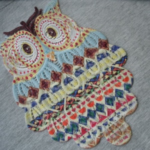 May include: A colorful owl design embroidered on a gray fabric. The owl is made of different colored threads and has a detailed design.