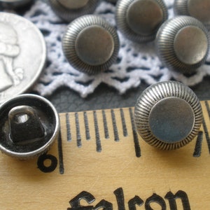 May include: Silver metal buttons with a raised, textured design. The buttons are approximately 1 inch in diameter.