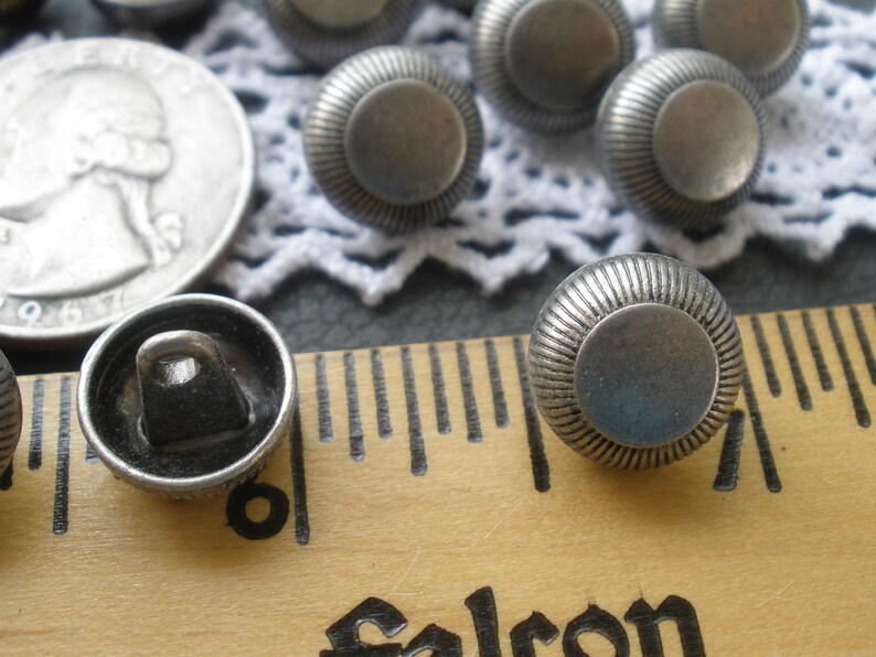May include: Silver metal buttons with a raised, textured design. The buttons are approximately 1 inch in diameter.