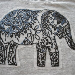 May include: A gray t-shirt with a black and blue sequined elephant design.