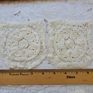 May include: Two white crocheted doilies with a circular design in the center. The doilies are approximately 4 inches in diameter and are laid out on a white fabric background.