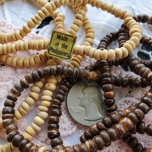 May include: A close-up of a pile of brown and natural wood bead necklaces. The necklaces are made in the Philippines, as indicated by the label.