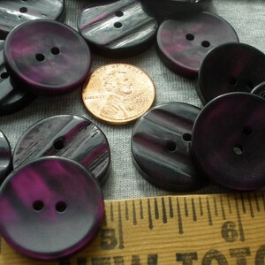 K&ouml;nnte beinhalten: Eine Sammlung von 15 dunkelvioletten Kn&ouml;pfen mit einem gestreiften Muster. Die Kn&ouml;pfe haben zwei L&ouml;cher und sind etwa 2,5 cm im Durchmesser.