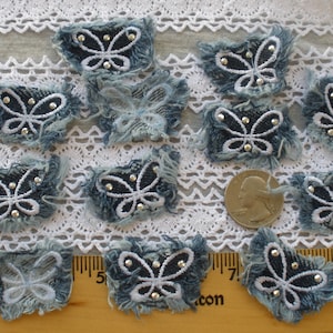 May include: Ten blue denim butterfly appliques with white stitching and silver rhinestones. The appliques are frayed around the edges and are arranged on a white lace background.
