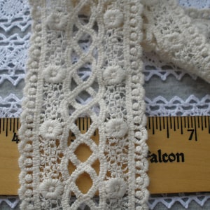 May include: White cotton lace trim with a repeating pattern of small circles and a larger circle in the center. The lace is measured against a wooden ruler with the numbers 4, 7, and 8 visible.