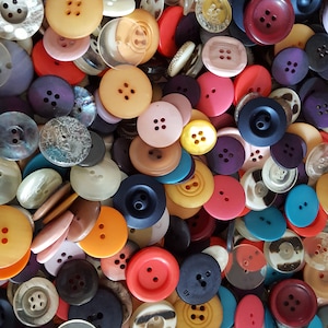 May include: A large collection of colorful buttons in various shapes and sizes. The buttons are made of plastic, metal, and fabric. Some buttons have two holes, while others have four holes. The buttons are a mix of solid colors and patterns.