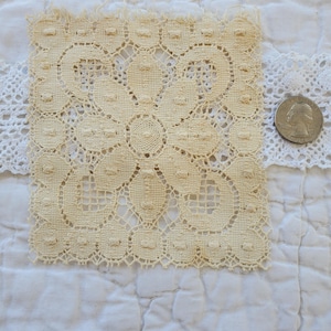 May include: A square piece of off-white crocheted lace with a repeating pattern of circles and loops.