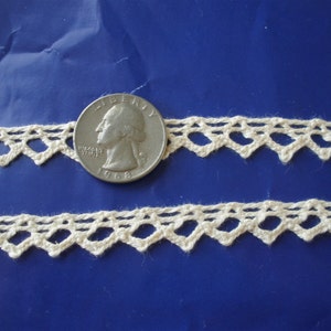May include: Two pieces of off-white crocheted lace trim with a diamond pattern. A US quarter is included for scale.
