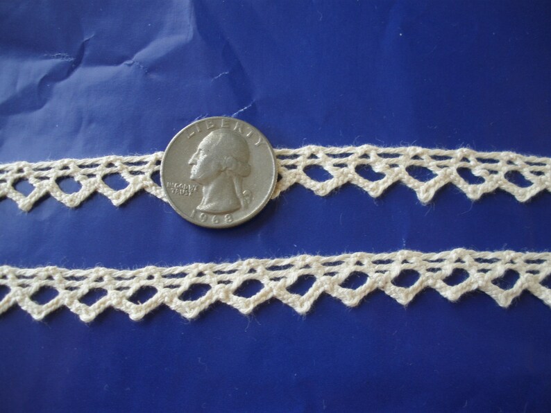 May include: Two pieces of off-white crocheted lace trim with a diamond pattern. A US quarter is included for scale.