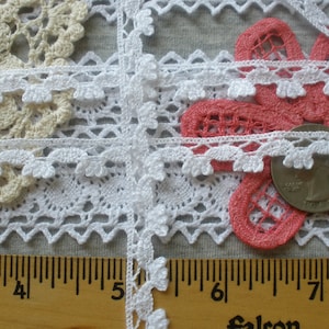 May include: White crochet lace trim with scalloped edges and a floral design. The trim is shown with a ruler measuring 7 inches.