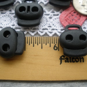 May include: Black plastic toggle clasps with two holes each. The clasps are shown next to a ruler with the number 6 visible. The word "Falcon" is printed on the ruler.