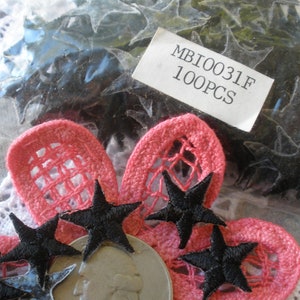 May include: A bag of 100 black star-shaped embellishments with a label that reads "MBI0031F 100PCS". The stars are shown on top of pink fabric flowers.