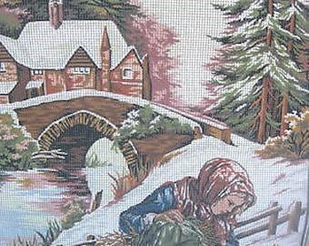 May include: A woman in a red and blue hooded cloak is kneeling in the snow, picking up a twig. She is in front of a stone bridge with a small house in the background. The scene is painted in a wintery landscape with snow-covered ground and trees.