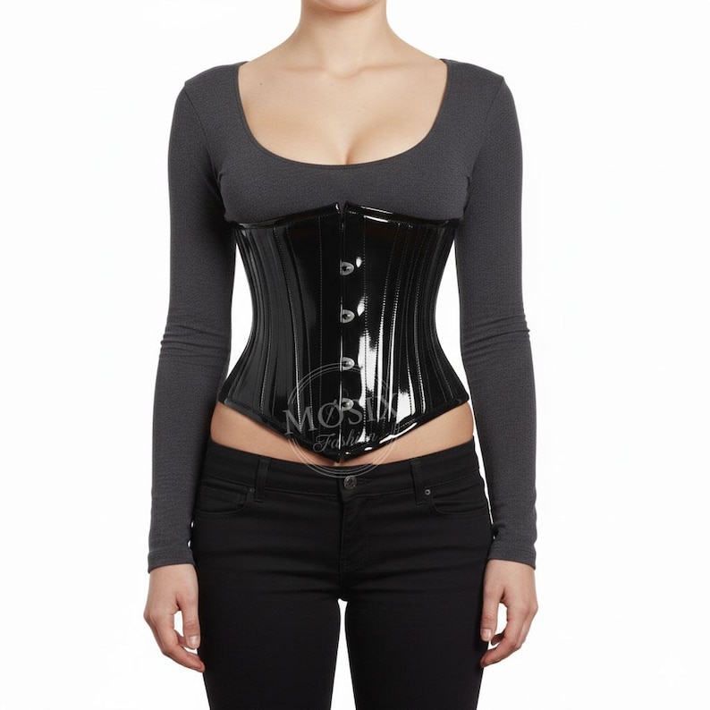 May include: A glossy black corset with vertical paneling and a button closure. The corset is worn over a gray long-sleeved top and black pants. The corset has a slight sheen and a fitted silhouette, typical of waist-cinching garments.