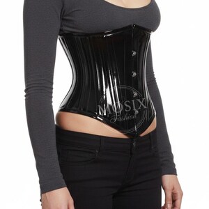 May include: A glossy black corset with vertical seam details and a button closure. The corset is worn over a long-sleeved gray top and black jeans. The text "MUSIX Fashion" is visible on the corset.