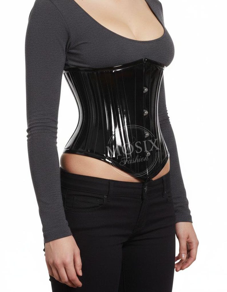 May include: A glossy black corset with vertical seam details and a button closure. The corset is worn over a long-sleeved gray top and black jeans. The text "MUSIX Fashion" is visible on the corset.