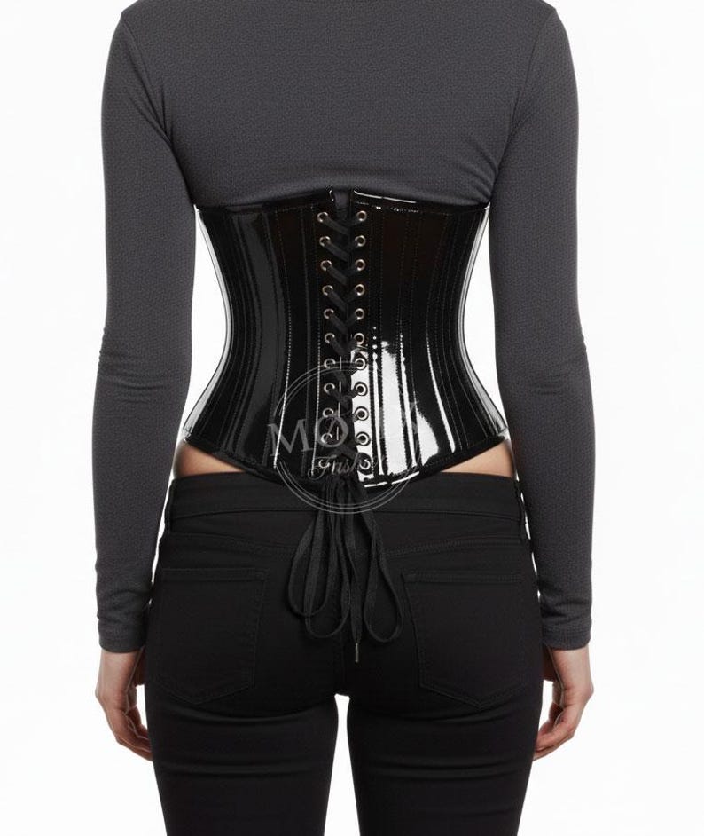 May include: A glossy black corset with vertical paneling and a lace-up back. The corset is worn over a long-sleeved gray top and black pants. The corset has a shiny, reflective surface.