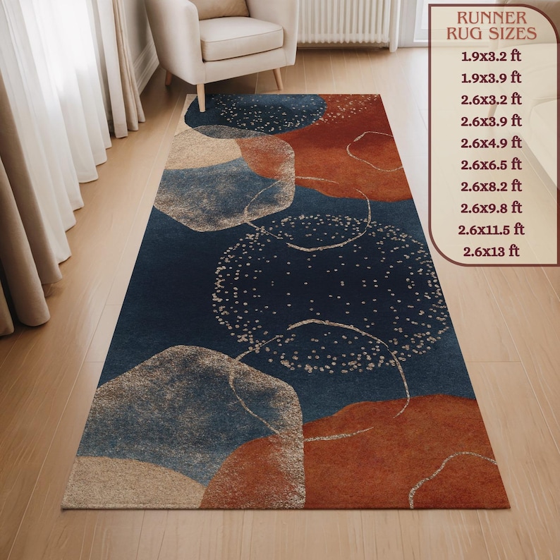 May include: A rectangular runner rug with an abstract design. The rug features a dark blue background with large, overlapping shapes in rust, beige, and light blue. The rug sizes are listed in the image. The rug is placed on a wooden floor.