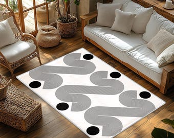 May include: A rectangular area rug featuring a white background with a repeating pattern of black, thin-lined, curved geometric shapes and solid black circles arranged in a rhythmic, flowing design across the entire surface of the floor covering.