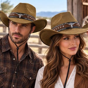 May include: Two olive green felt cowboy hats featuring a black leather hatband adorned with silver-toned studs and a central silver-toned longhorn steer skull emblem. Each hat includes a thin black chin cord with an adjustable sliding toggle.
