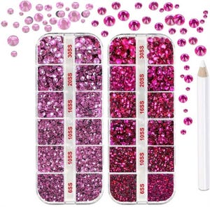 May include: Two plastic organizers filled with various sizes of pink rhinestones, labelled 6SS to 30SS. Loose rhinestones are scattered around the organizers. A white pencil is on the right side of the image. Ideal for nail art and crafts.