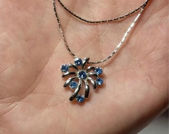 Silver-colored pendant with blue stones on a chain.