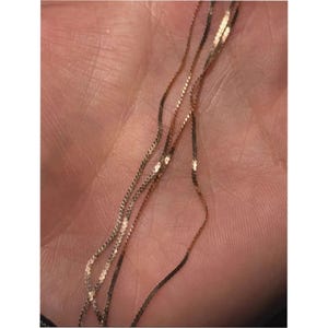 May include: A delicate rose gold chain necklace featuring a fine, shimmering link design. The thin, metallic strands are intertwined, creating a subtle and reflective appearance with a warm, pinkish-gold hue throughout the entire piece.