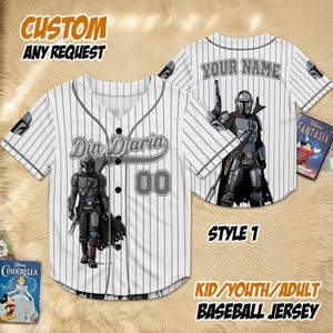 May include: White baseball jersey with grey pinstripes, featuring a Din Djarin graphic and the text "Din Djarin" and "00". The jersey also has the text "YOUR NAME" on the back and "STYLE 1". The text "CUSTOM ANY REQUEST" and "KID/YOUTH/ADULT BASEBALL JERSEY" are also visible.