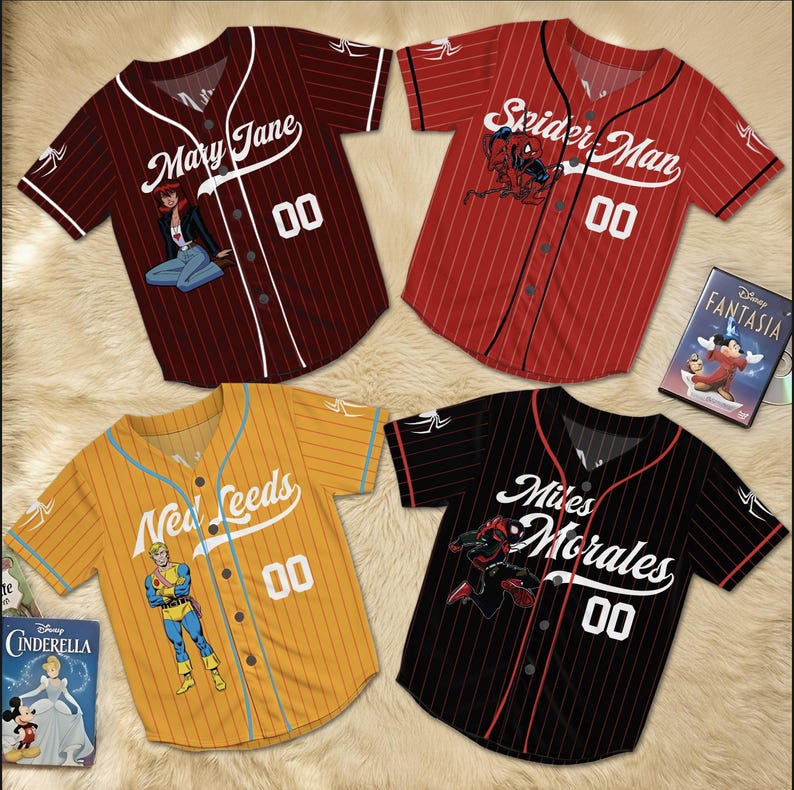 May include: Four baseball jerseys with comic book themes. The jerseys are maroon, red, yellow, and black with white lettering and the number "00". The maroon jersey says "Mary Jane", the red jersey says "Spider Man", the yellow jersey says "New Leeds", and the black jersey says "Miles Morales".
