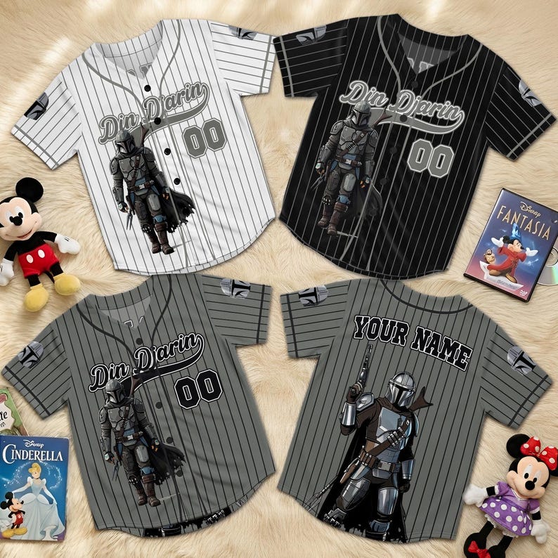 May include: Four baseball jerseys. One white, one black, and two grey, all with pinstripes. Each has the text "Din Djarin" and "00", and a character graphic. One grey jersey has "Your Name" on the back. The jerseys are for sale.