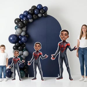 May include: A party scene with a navy blue backdrop, a balloon arch, and three cardboard cutouts of a superhero. A woman and a young boy are also in the image. The balloons are in shades of blue, gray, and black.