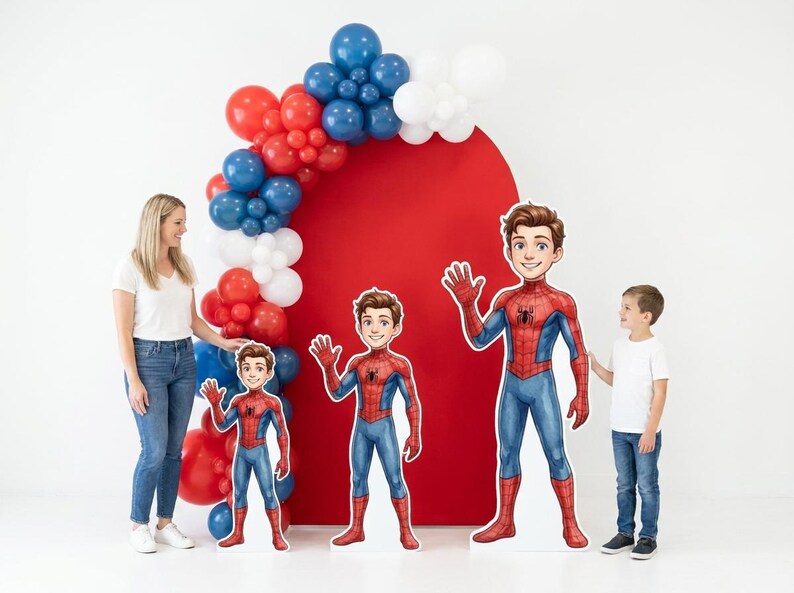 May include: A party scene with a red backdrop and balloon arch in red, white, and blue. Three Spider-Man cutouts of varying sizes stand in front. A woman and a boy are also present.