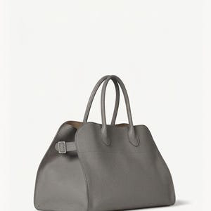 Peut inclure: Un sac fourre-tout en cuir gris avec deux poign&eacute;es sup&eacute;rieures et une forme rectangulaire. Le sac est dot&eacute; d'une fermeture &agrave; boucle sur le c&ocirc;t&eacute; et d'une surface textur&eacute;e. L'int&eacute;rieur est de couleur marron clair.