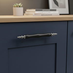 May include: A close-up of a navy blue cabinet door featuring a black and silver handle. The handle has a cylindrical, dark shape with decorative silver detailing at each end. The handle is a stylish addition.