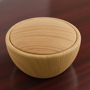 May include: A light-colored wooden bowl with a matching lid. The bowl has a rounded shape and a smooth, polished finish. The wood grain is visible on both the bowl and the lid, creating a natural aesthetic. The bowl is likely used for storage or display.