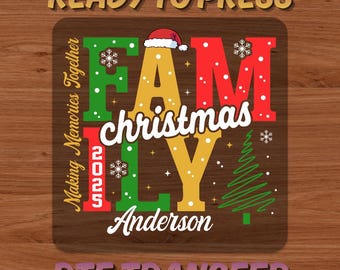 May include: A brown DTF transfer with the words "READY TO PRESS" and "DTF TRANSFER" in a gradient font. The design features the word "FAMILY" in red, green, and yellow, with "christmas" in white, a Santa hat, snowflakes, and a Christmas tree.