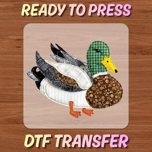 May include: A DTF transfer featuring a detailed duck design. The duck has a green plaid head, a brown floral patterned body, and wings with gray, black, and white patterns. The text "READY TO PRESS" and "DTF TRANSFER" are displayed above and below the duck.