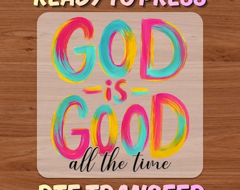 May include: A rectangular DTF transfer with the words "READY TO PRESS" and "DTF TRANSFER" in a bubble font. The words "GOD is GOOD all the time" are in a colorful, brushstroke style. The background has a wood grain texture.